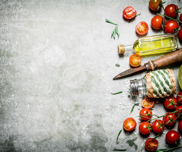 Tomates en el fondo. Tomates frescos, aceite de oliva y especias. Sobre un fondo de piedra.