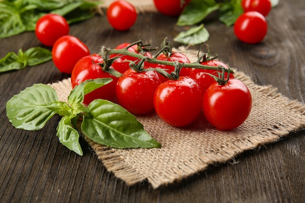 Tomates frescos con albahaca en la mesa de madera de cerca