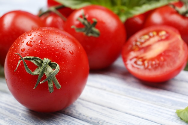 Tomates frescos con albahaca en la mesa de madera de cerca