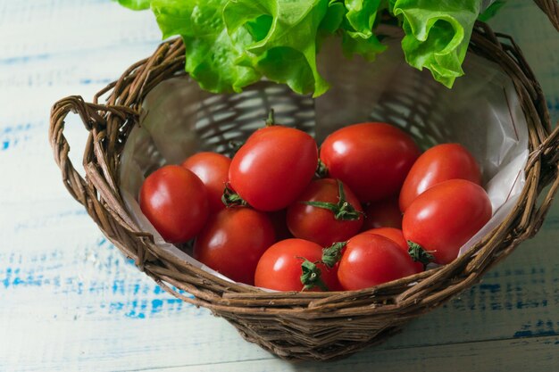 Tomates frescos en una cesta sobre un fondo de madera