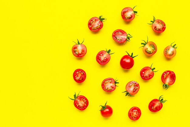 Tomates frescos, corte inteiro e meio isolado em fundo amarelo.