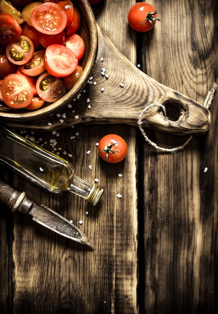 Foto tomates frescos en un cuenco de madera con aceite de oliva