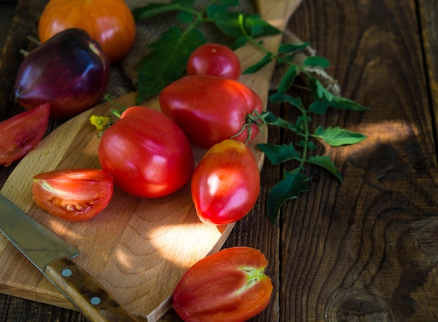 Tomates frescos de fazenda em uma tábua em uma mesa de madeira velha