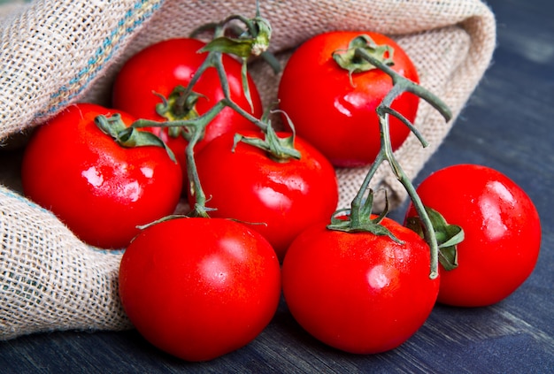 tomates frescos em saco de serapilheira em madeira