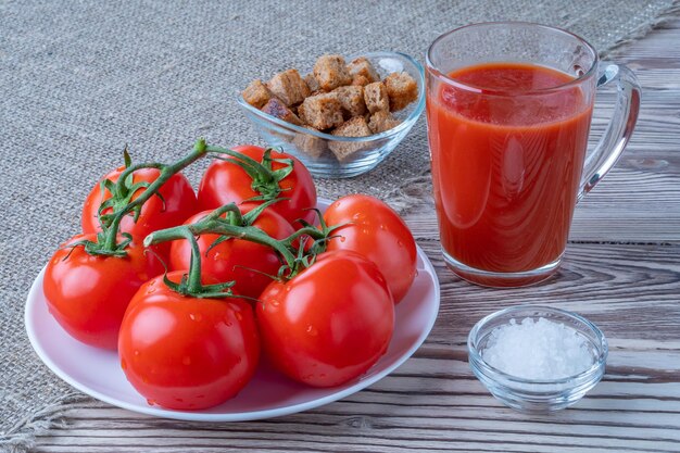 Tomates frescos jugo de tomate con sal una taza de jugo de tomates en el pan rallado de fondo dri