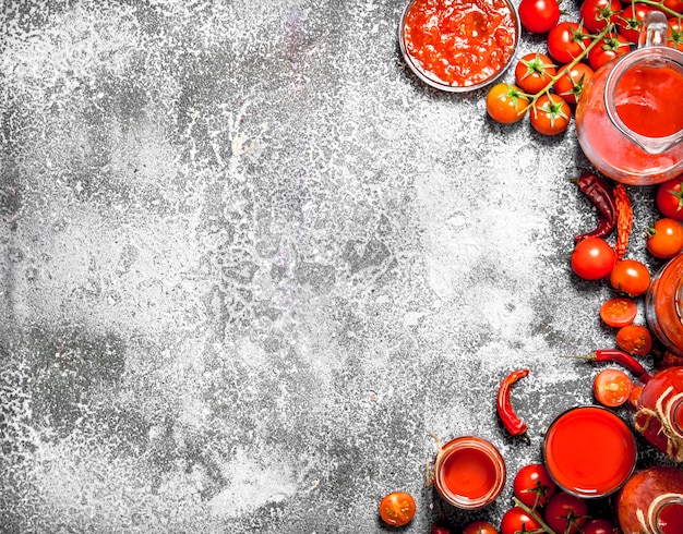 Tomates frescos, jugo de tomate y salsa. Sobre mesa rústica.