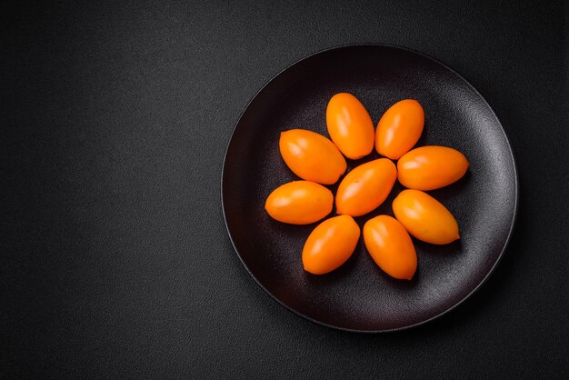 Tomates frescos y jugosos en forma de ciruela amarillos brillantes sobre un fondo de hormigón de textura negra