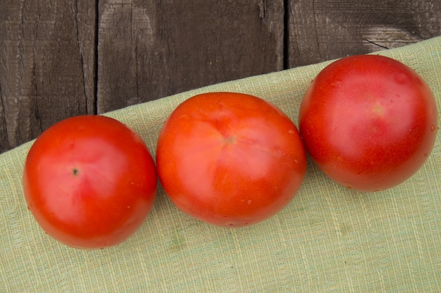 Tomates frescos, maduros en una servilleta, fondo de madera oscuro