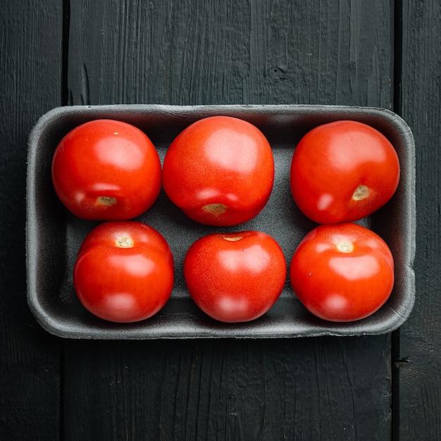 Tomates frescos orgânicos vermelhos, na mesa de madeira preta