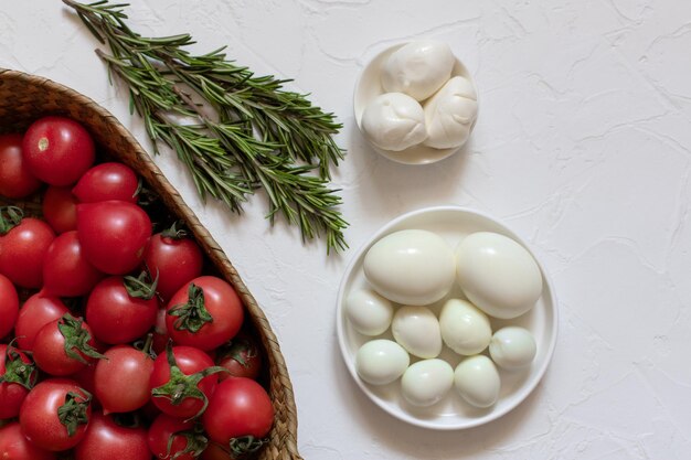 Tomates frescos, pepinos, ovos de galinha e alguns raminhos de alecrim em uma cesta de vime