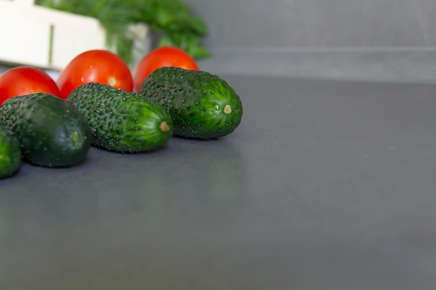 Tomates frescos pepinos verdes e salada verde perfumada em uma cesta de bambu disposta exatamente em uma fileira na mesa da cozinha