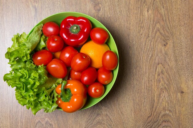 tomates frescos, pimienta y lechuga sobre fondo de madera