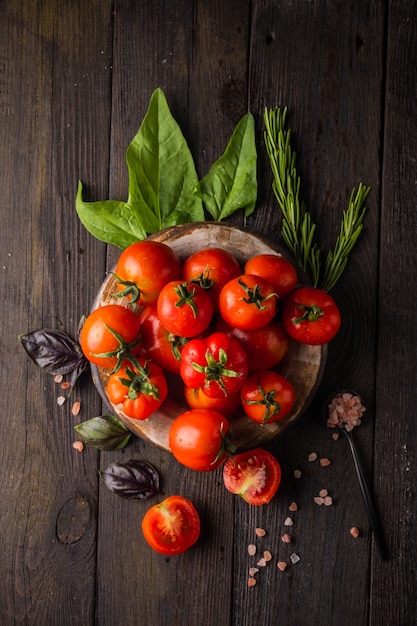 Tomates frescos en un plato sobre un fondo oscuro cosechando tomates