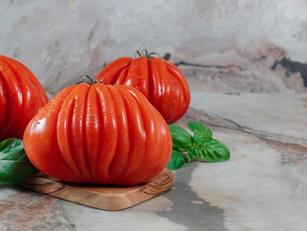 Tomates frescos Raf Coeur De Boeuf y albahaca sobre un fondo marrón