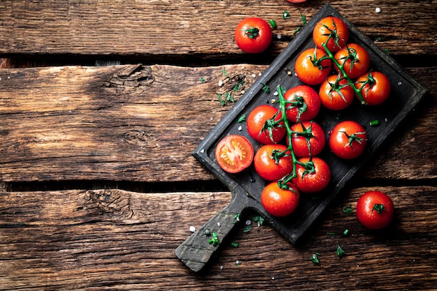 Tomates frescos en una rama sobre una tabla para cortar