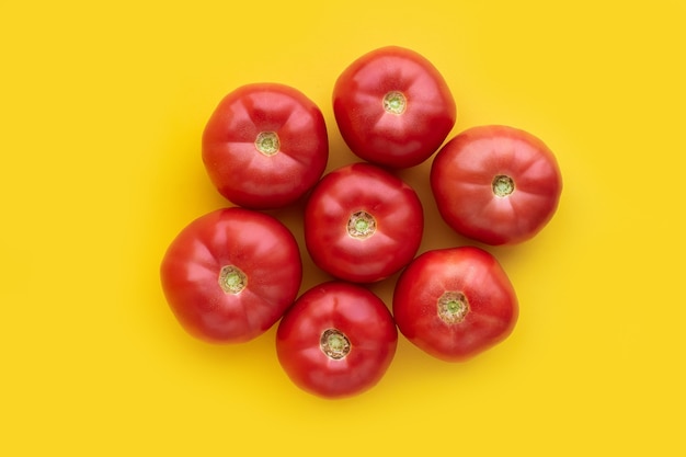 Foto tomates frescos rojos jugosos maduros sobre fondo amarillo. vegetales eco natural bio. patrón de minimalismo