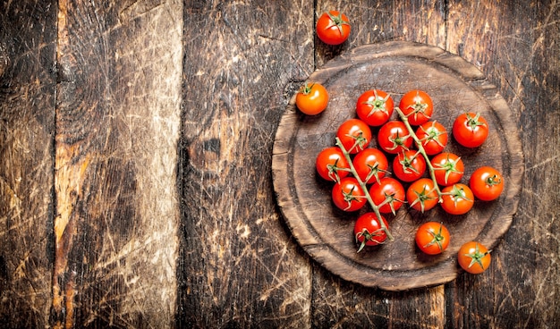 tomates frescos en el tablero viejo. Sobre mesa de madera.