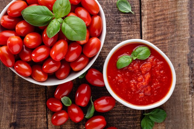 Tomates frescos en un tazón sobre una vieja mesa de madera Fondo de tomate Verduras saludables y hojas de albahaca