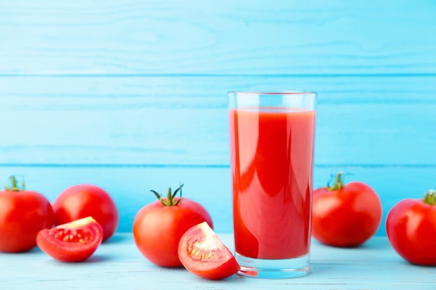 Tomates frescos con un vaso alto de jugo