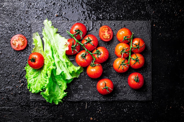 Tomates con hojas de lechuga sobre una placa de piedra