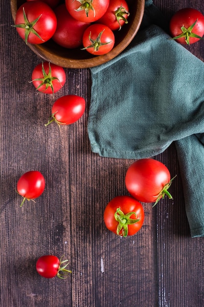 Tomates inteiros frescos em uma mesa de madeira e em uma tigela Alimentos orgânicos Vista superior e vertical