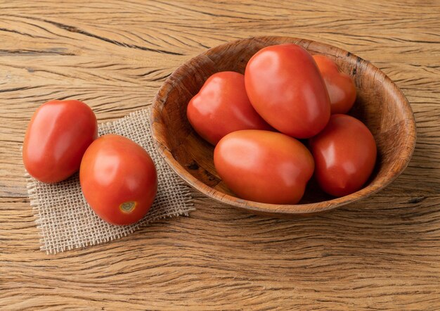 Tomates italianos em uma tigela sobre a mesa de madeira