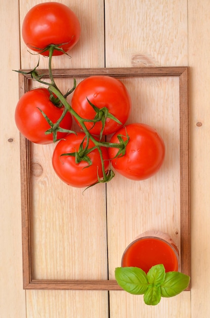 Tomates y jugo de tomate sobre un fondo de madera en un marco