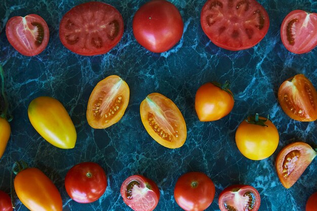 Tomates laranja e amarelos vermelhos coloridos sobre fundo de mármore verde Alimentos orgânicos naturais Comida de vista superior