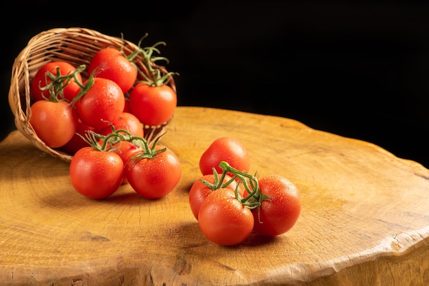 Tomates, lindos tomates caindo de uma cesta de palha em madeira rústica, foco seletivo.