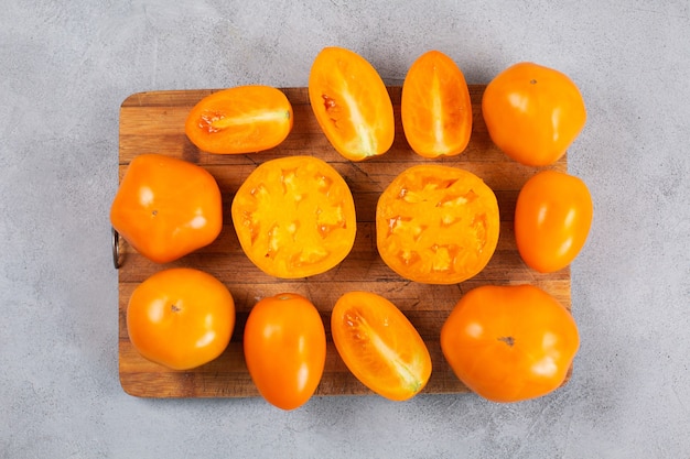 Tomates maduros e frescos de laranja amarela em uma tábua