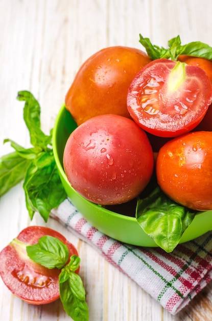 Foto tomates maduros e manjericão na tigela verde.