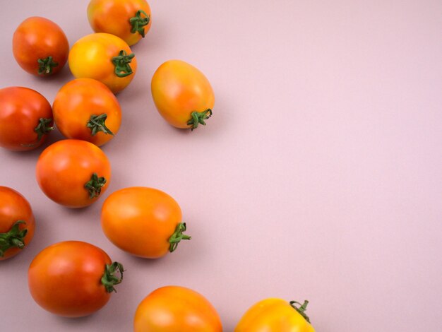 Tomates maduros frescos amarillos y rojos sobre fondo gris neutro