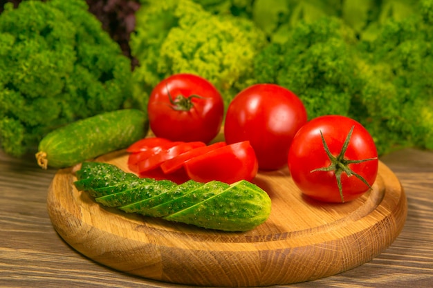 Tomates maduros frescos em uma mesa de madeira com uma salada verde