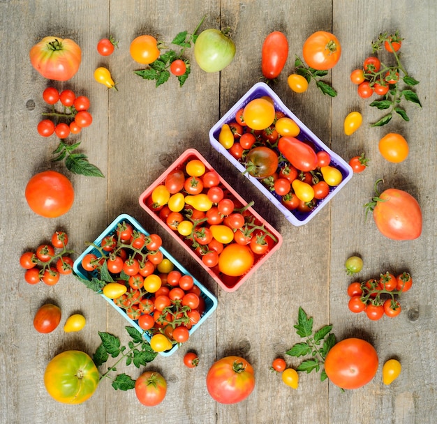 Los tomates maduros frescos están en la caja en la vista superior de la mesa de madera