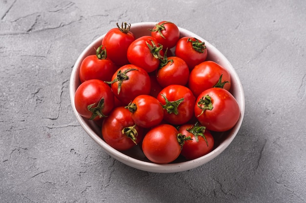 Tomates maduros frescos con gotas de agua en un tazón