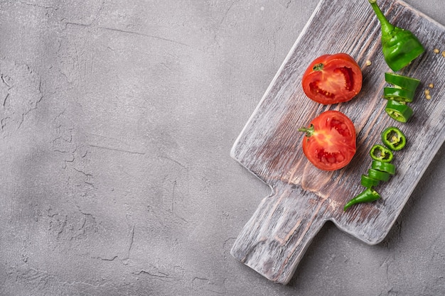 Tomates maduros frescos en rodajas con pimientos picantes en la tabla de cortar de madera vieja
