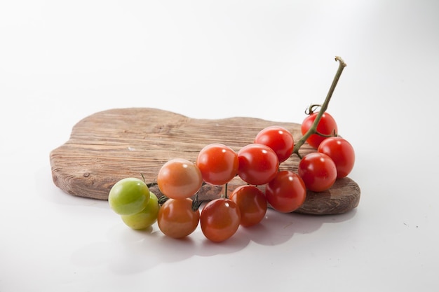 Tomates maduros en mentira sobre una tabla de cortar sobre un fondo blanco.