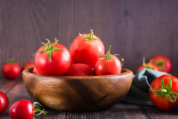 Tomates maduros orgânicos em uma tigela sobre uma mesa de madeira colheita e produtos locais