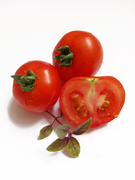 tomates maduros y ramita de albahaca sobre un fondo blanco