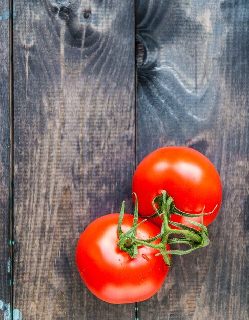 Tomates maduros vermelhos frescos em um galho em um fundo de madeira