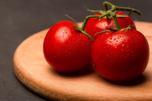 Tomates maduros vermelhos na placa de madeira fechar