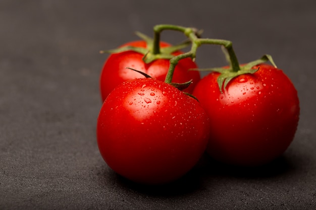 Tomates maduros vermelhos na placa de madeira fechar