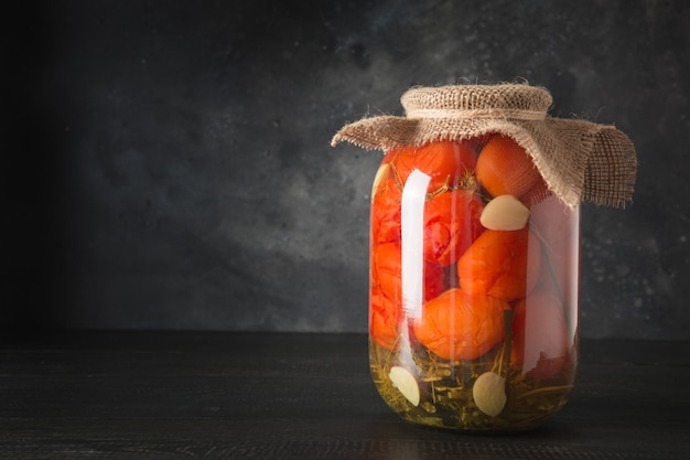 Tomates marinados caseiros Legumes enlatados em potes de vidro na placa de madeira