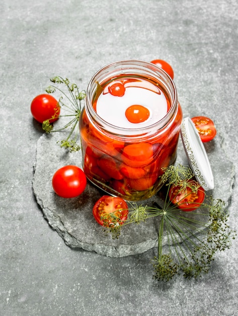 Tomates marinados con hierbas. Sobre un fondo de piedra.