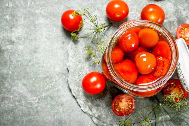 Tomates marinados con hierbas. Sobre un fondo de piedra.