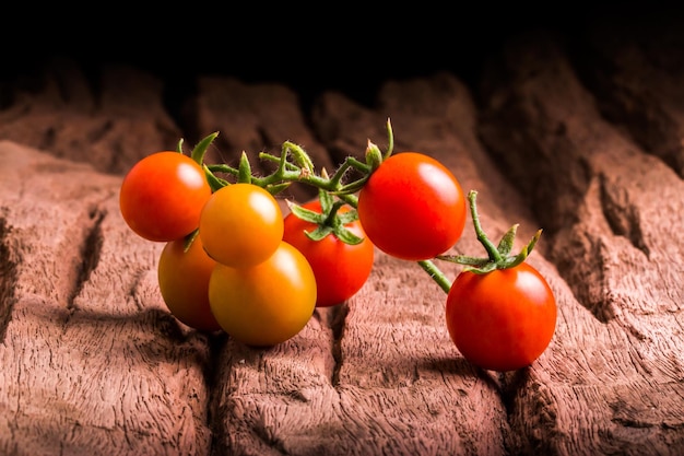 Tomates na placa de madeira no fundo preto