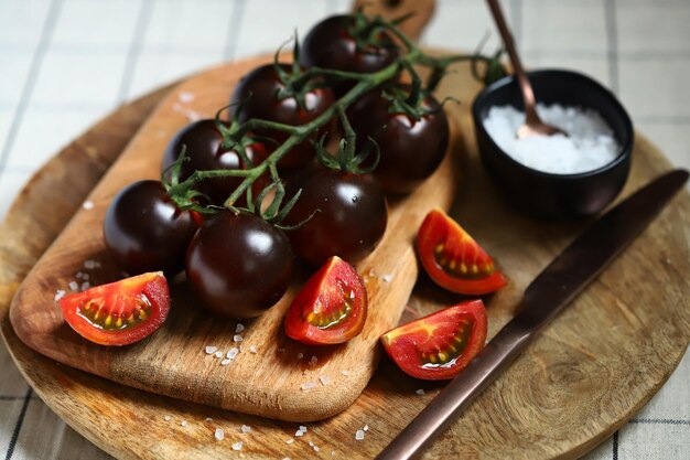 Tomates negros con sal marina en una tabla de madera