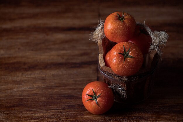 Tomates no balde vintage na mesa de madeira