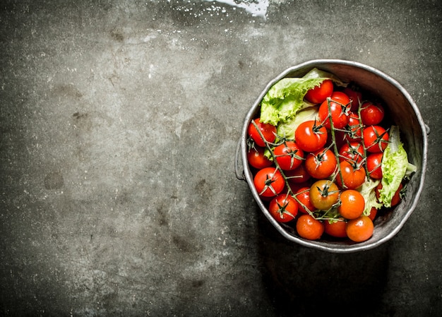 Tomates en la olla vieja. Fondo de piedra mojada.