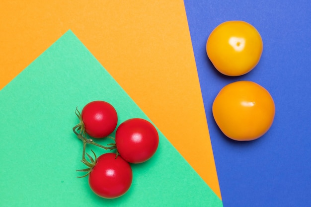 tomates orgánicos de diferentes colores sobre fondo verde, naranja y azul